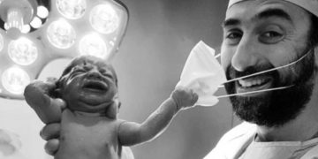Fotografia care a zguduit internetul! Un nou-născut smulge masca medicului, imediat după ce a venit pe lume