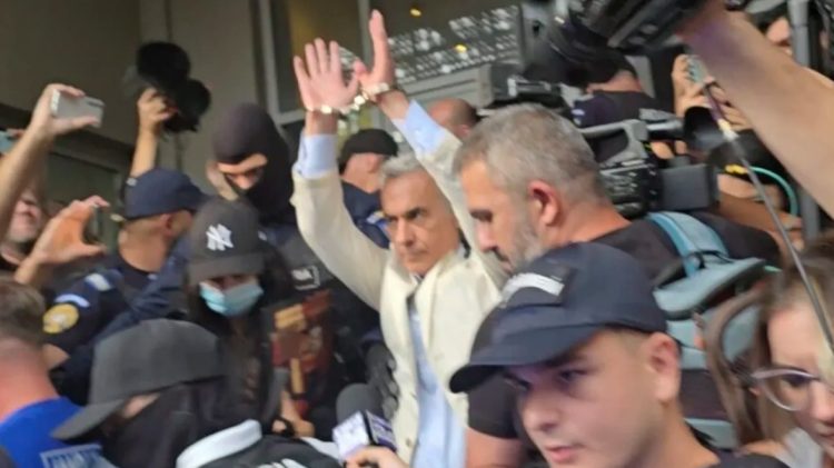 Călin Georgescu ridică mâinile încătușate la ieșirea de la DIICOT pentru a fi dus în arest